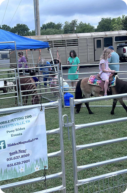 Mobile petting zoo pony rides at an outdoor event